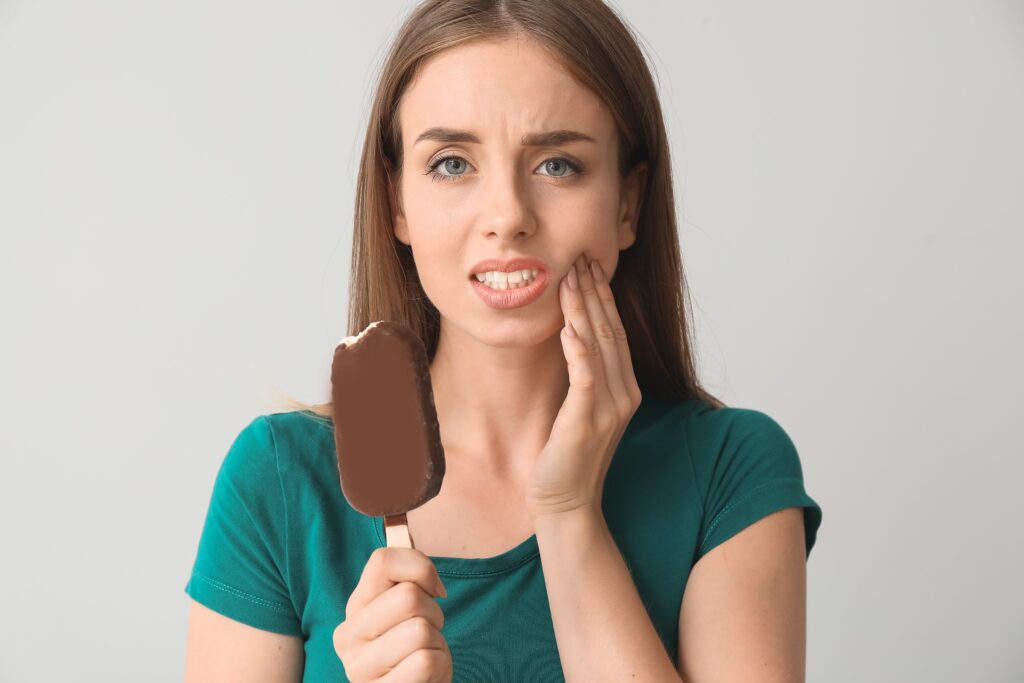 young woman with sensitive teeth cold ice cream grey min