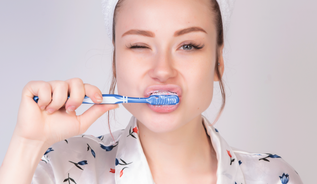 An image of a woman brushing her teeth, demonstrating proper oral care.