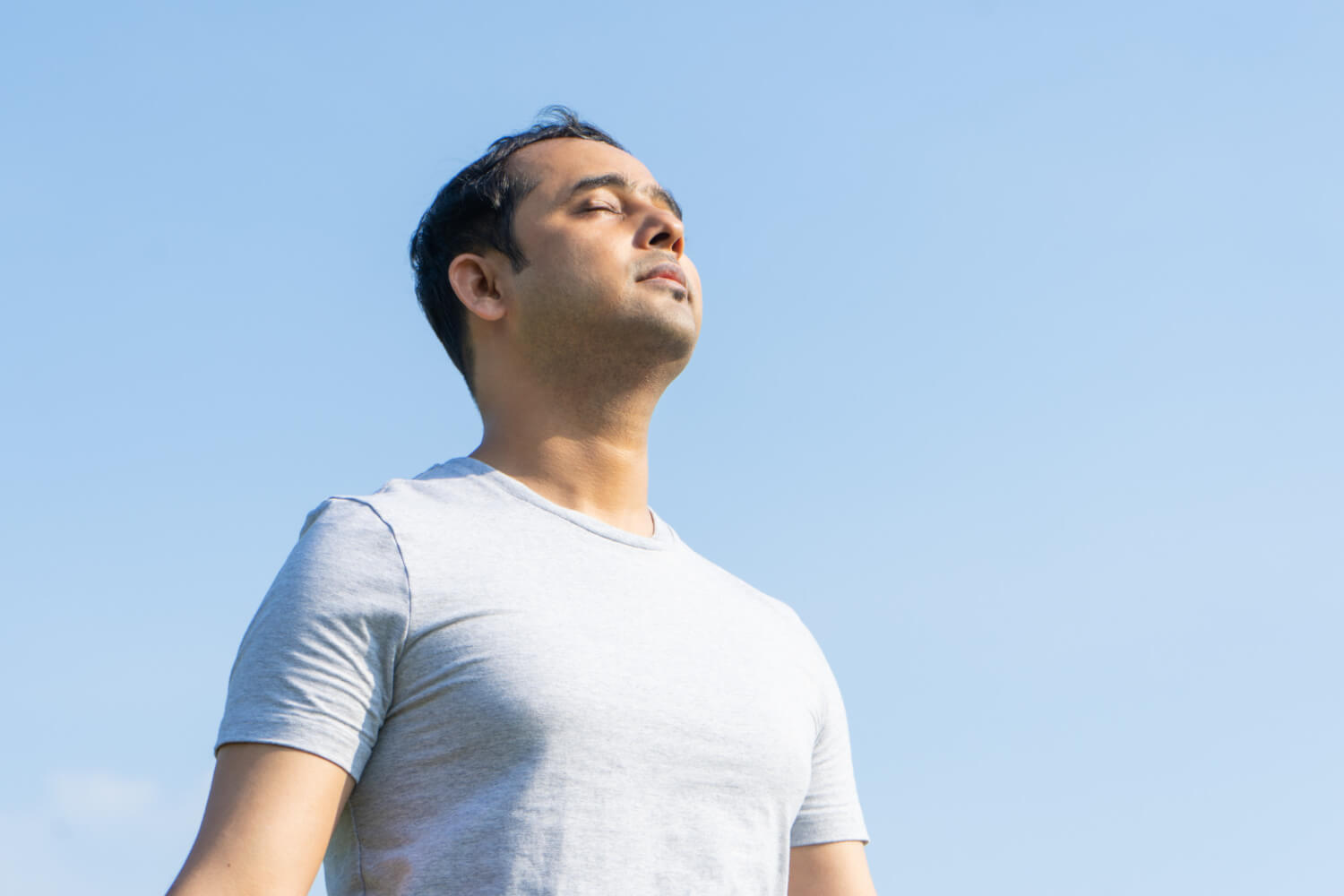 Indian man sitting outdoors with his eyes closed, hands together in a peaceful pose. Painless Injection