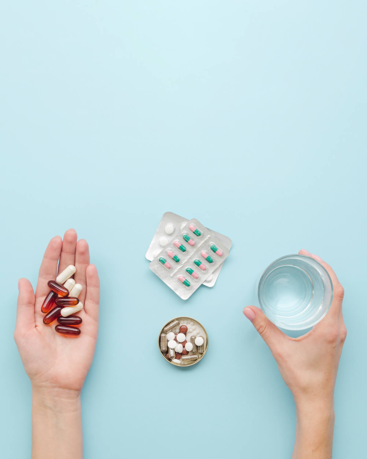 Hands holding pills and a glass of water, preparing for oral sedation before a dental procedure