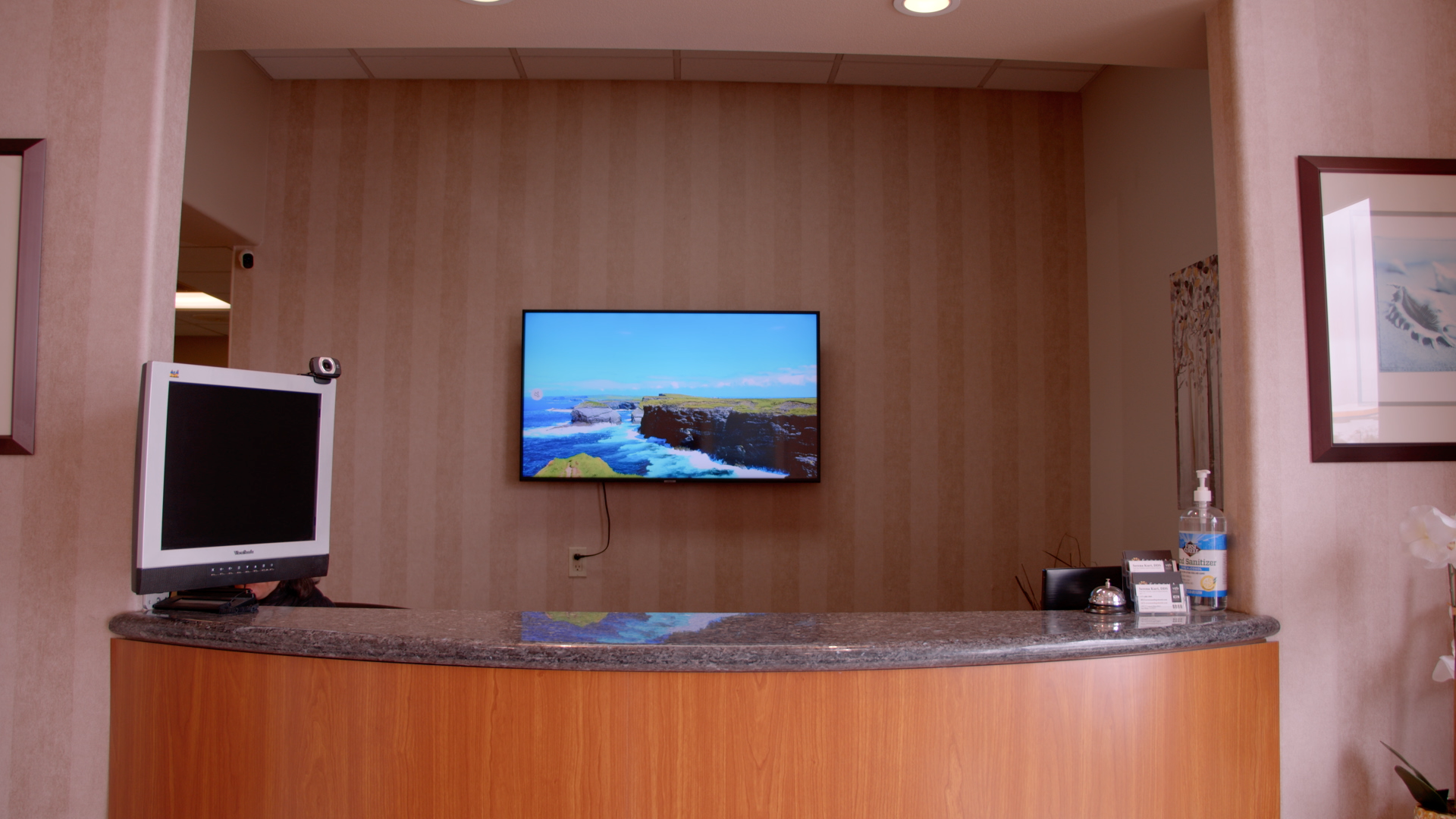 A photograph showcasing the reception area at Serena Family & Cosmetic Dentistry, featuring a nature-themed display on a screen