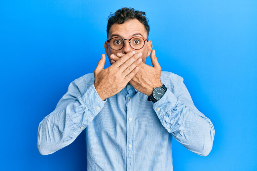 Dental Phobia Young Hispanic man covering mouth with hands, looking secretive